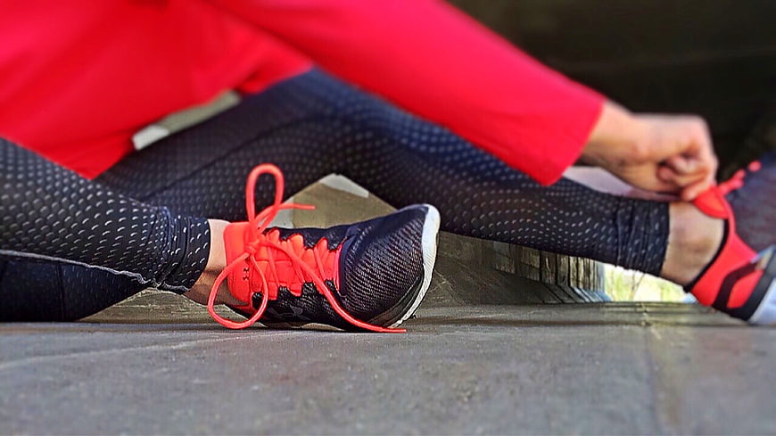 Runner tying shoelaces on wooden steps before workout