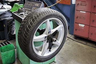 Car wheel mounted on tire balancing machine in auto repair shop
