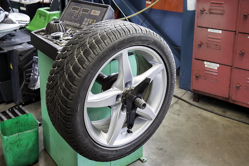 Car wheel mounted on tire balancing machine in auto repair shop