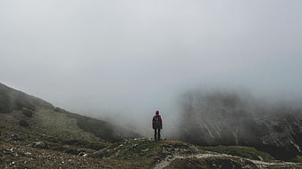 Solitary Hiker Standing On Misty Mountain Ridge