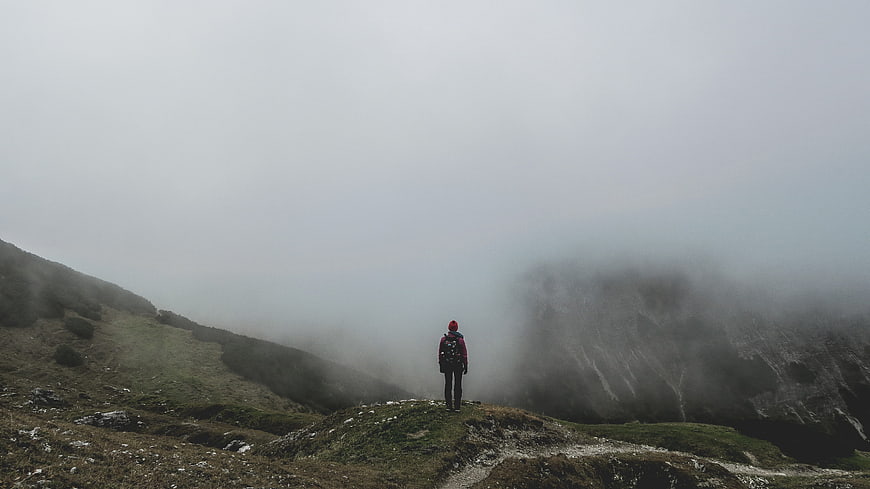 Solitary Hiker Standing On Misty Mountain Ridge