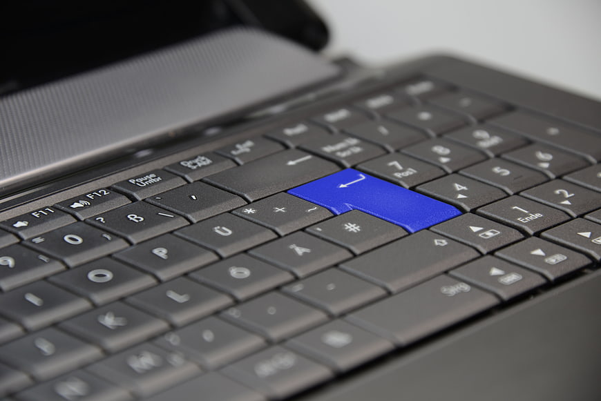 Close-up of laptop keyboard with blue enter key