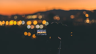 Camera on tripod capturing city bokeh at sunset