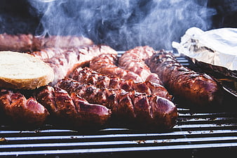 Sizzling sausages grilling on barbecue with smoke
