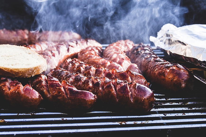 Sizzling sausages grilling on barbecue with smoke