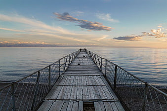 Weathered Wooden Pier Extending into Calm Sea at Sunset