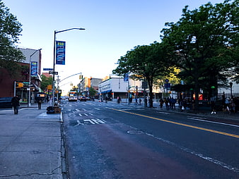 Urban street scene with pedestrians and trees in late afternoon