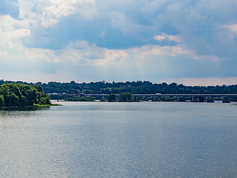 Wide River Landscape with Bridge and Cloudy Sky
