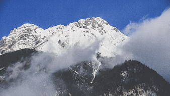 Snow-Capped Mountain Peak Rising Through Clouds