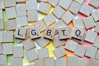 Scrabble Tiles Spelling LGBTQ on Rainbow Background