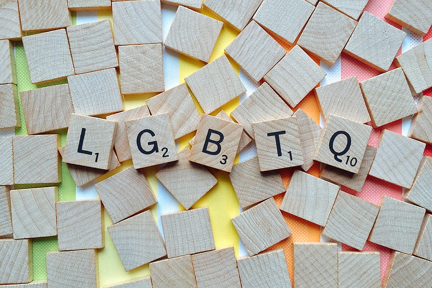 Scrabble Tiles Spelling LGBTQ on Rainbow Background