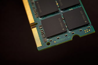 Close-up of green RAM stick with gold pins on dark background