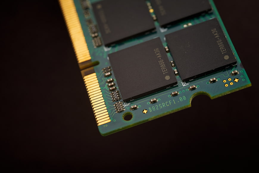 Close-up of green RAM stick with gold pins on dark background
