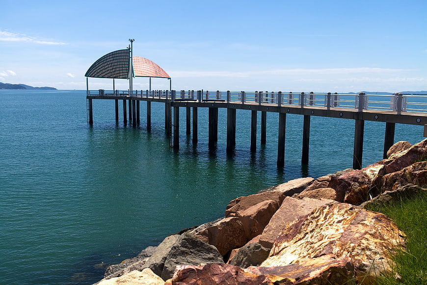 Modern wooden pier extending over calm turquoise ocean water