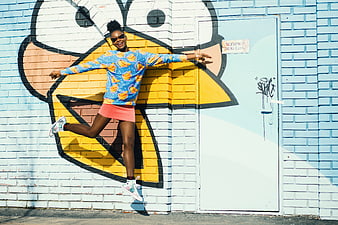 Happy woman jumping in front of colorful street art mural