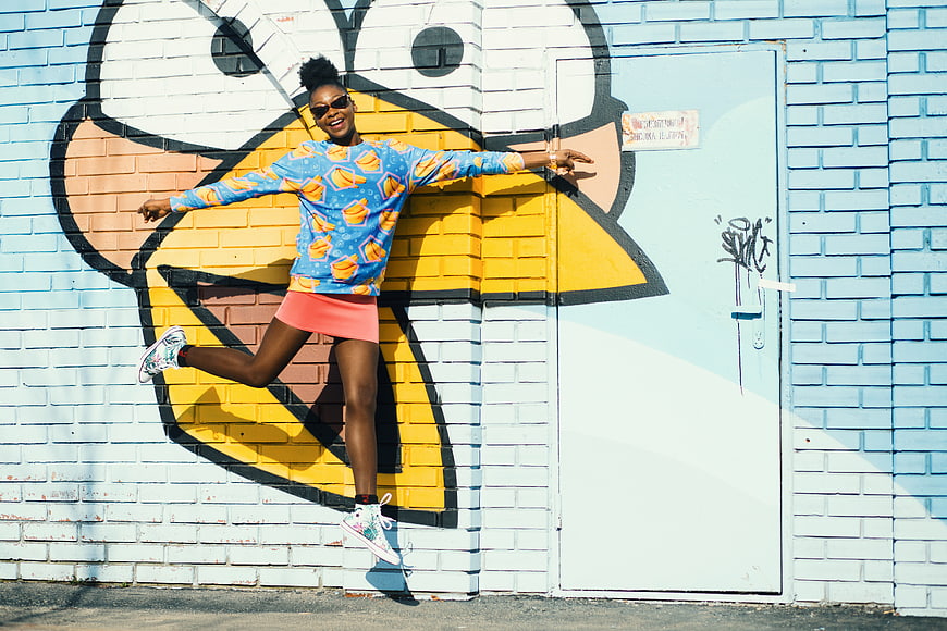 Happy woman jumping in front of colorful street art mural