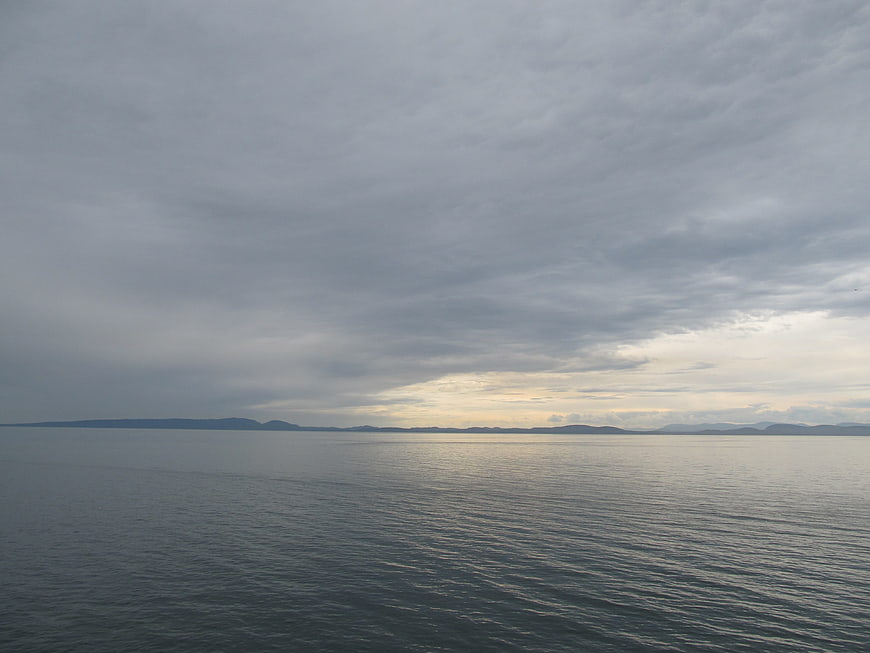 Serene Ocean View Under Overcast Sky with Distant Mountains
