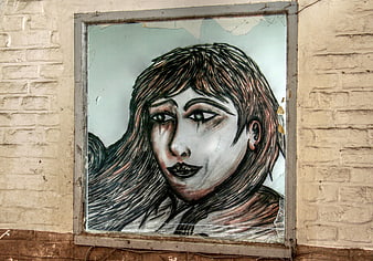 Hand-drawn portrait of a woman on a broken window in an abandoned building