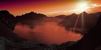 Dramatic Sunset Over Mountain Lake with Sunburst
