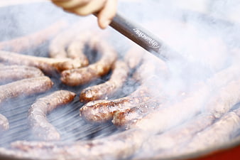 Sizzling sausages grilling on a barbecue with smoke