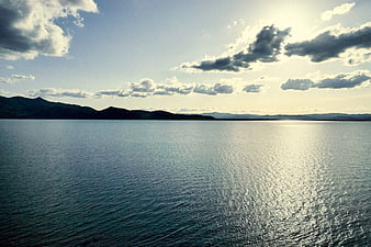 Serene Lake Landscape with Sunlight Reflection and Distant Mountains
