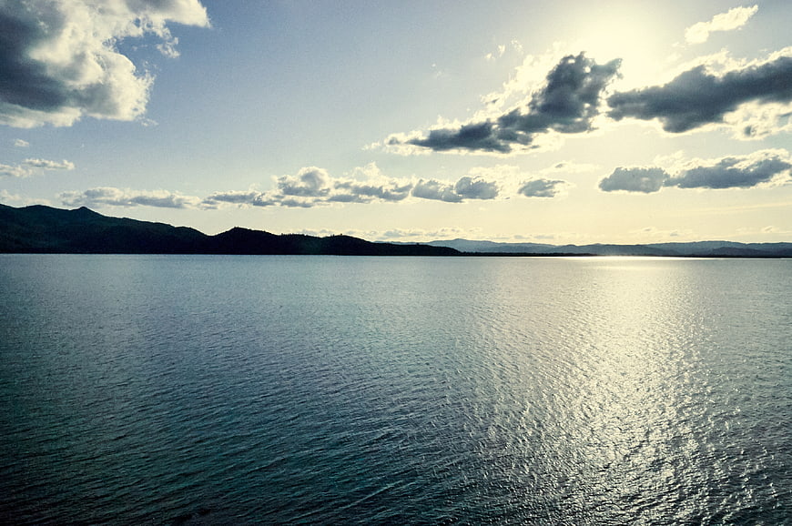 Serene Lake Landscape with Sunlight Reflection and Distant Mountains