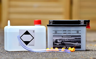 Motorcycle battery and acid refill container on pavement