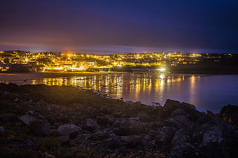 Coastal town illuminated at twilight with reflections on water