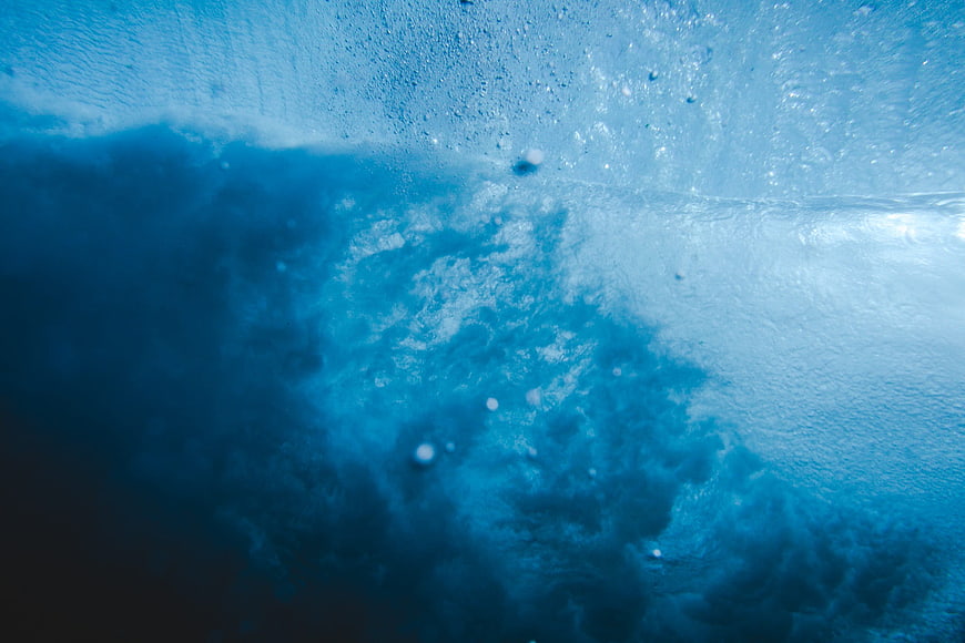Underwater view of turbulent blue ocean waves and bubbles