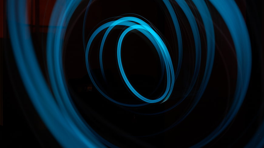 Abstract blue light trails forming concentric circles on black background