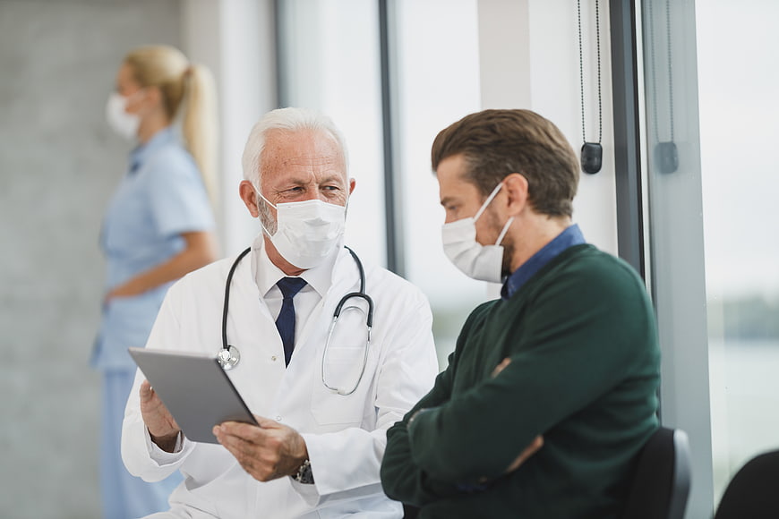 Senior Doctor Consulting Patient with Tablet in Hospital