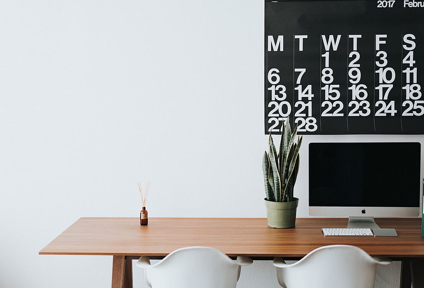 Minimalist office desk with computer and wall calendar