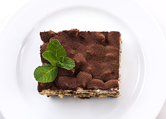 Top View of Tiramisu Slice with Mint Garnish on White Plate
