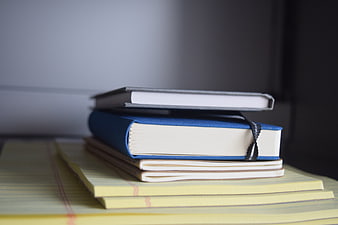 Stack of Notebooks and Books on a Desk