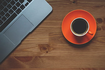 Flat lay of laptop and orange coffee cup on wooden desk