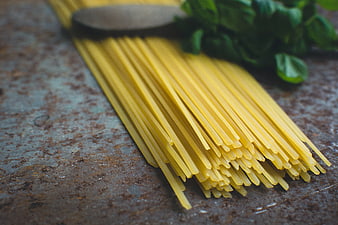 Uncooked spaghetti pasta with fresh basil on rustic surface
