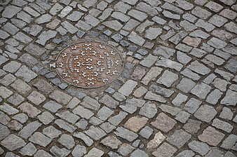 Rusted manhole cover on cobblestone street texture