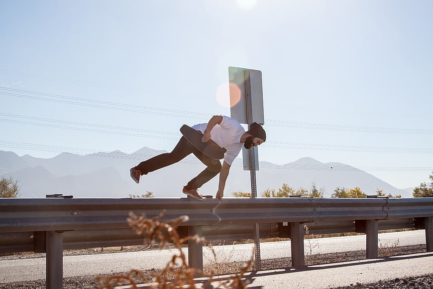 Skateboarder Grinding on Highway Guardrail with Mountain Background