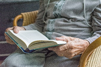 Close-up of elderly woman's hands holding an open book