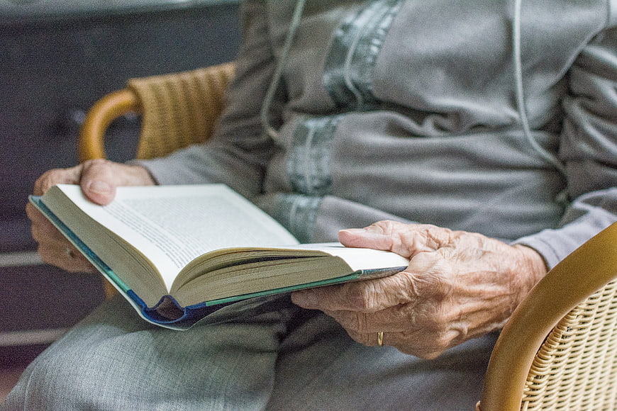 Close-up of elderly woman's hands holding an open book