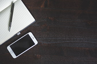 Minimalist workspace with smartphone and notebook on dark wood