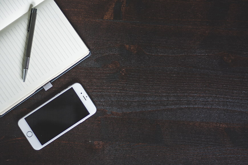 Minimalist workspace with smartphone and notebook on dark wood