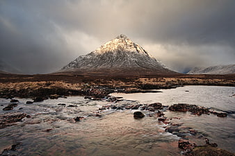Dramatic Snow-Capped Mountain Peak with Flowing River Foreground