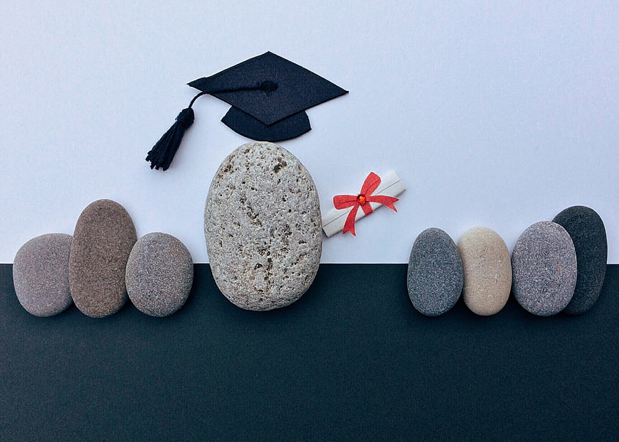 Graduation cap and diploma on stones concept