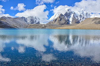 Serene turquoise lake reflecting snow-capped mountains and blue sky