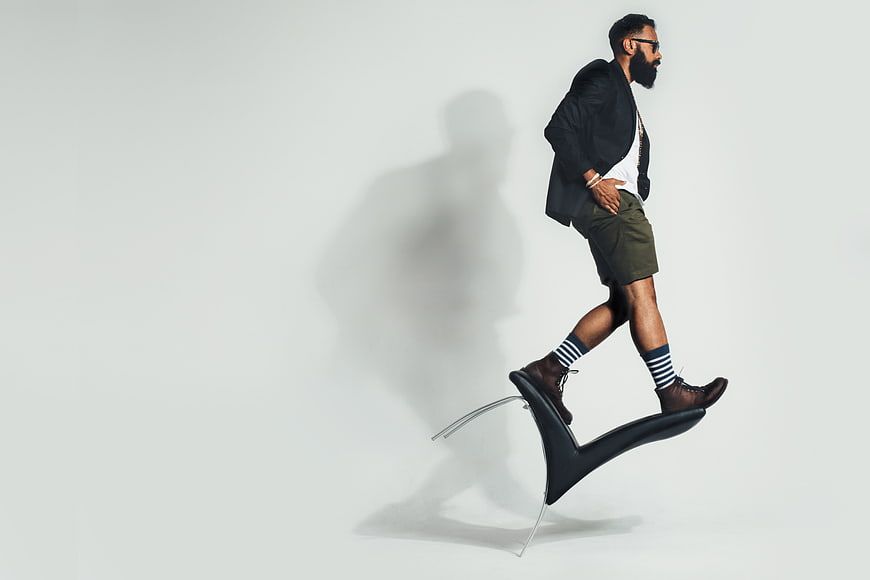 Stylish bearded man balancing on a modern chair