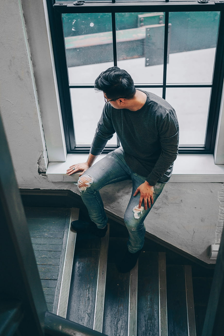 Man Sitting on Staircase Landing by Window