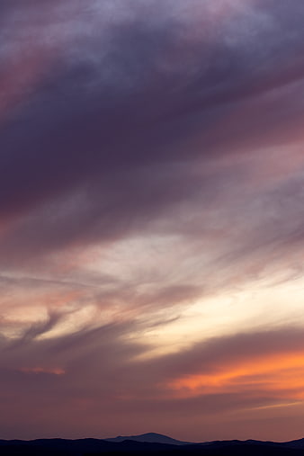 Dramatic purple and orange sunset sky over mountain silhouette