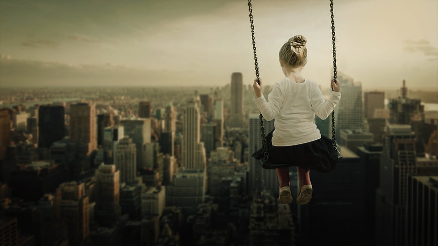 Little girl on swing high above city skyline