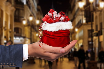 Hand holding Christmas gift sack on blurred city street
